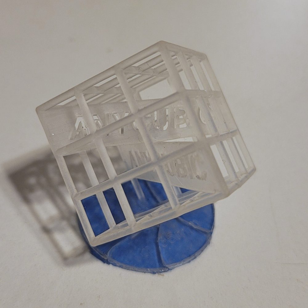 Un cube ajouré translucide imprimé en résine, posé sur son support
