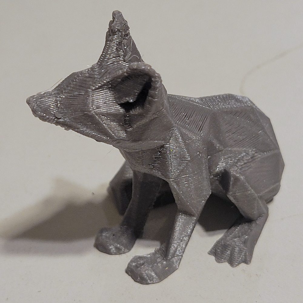 Un renard à facettes géométriques imprimé en filament gris, vu de face